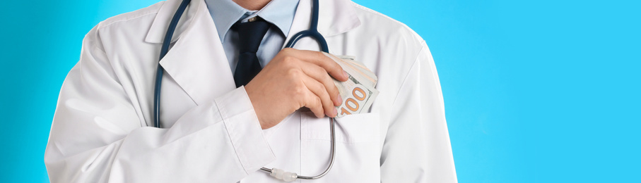 Doctor putting bribe into pocket on light blue background, closeup. Banner design