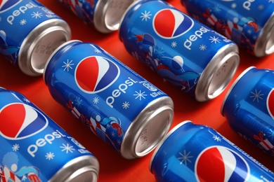 Photo of MYKOLAIV, UKRAINE - FEBRUARY 08, 2021: Cans of Pepsi on red background, closeup