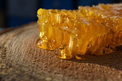 Photo of Piece of fresh honeycomb on wood stump, closeup