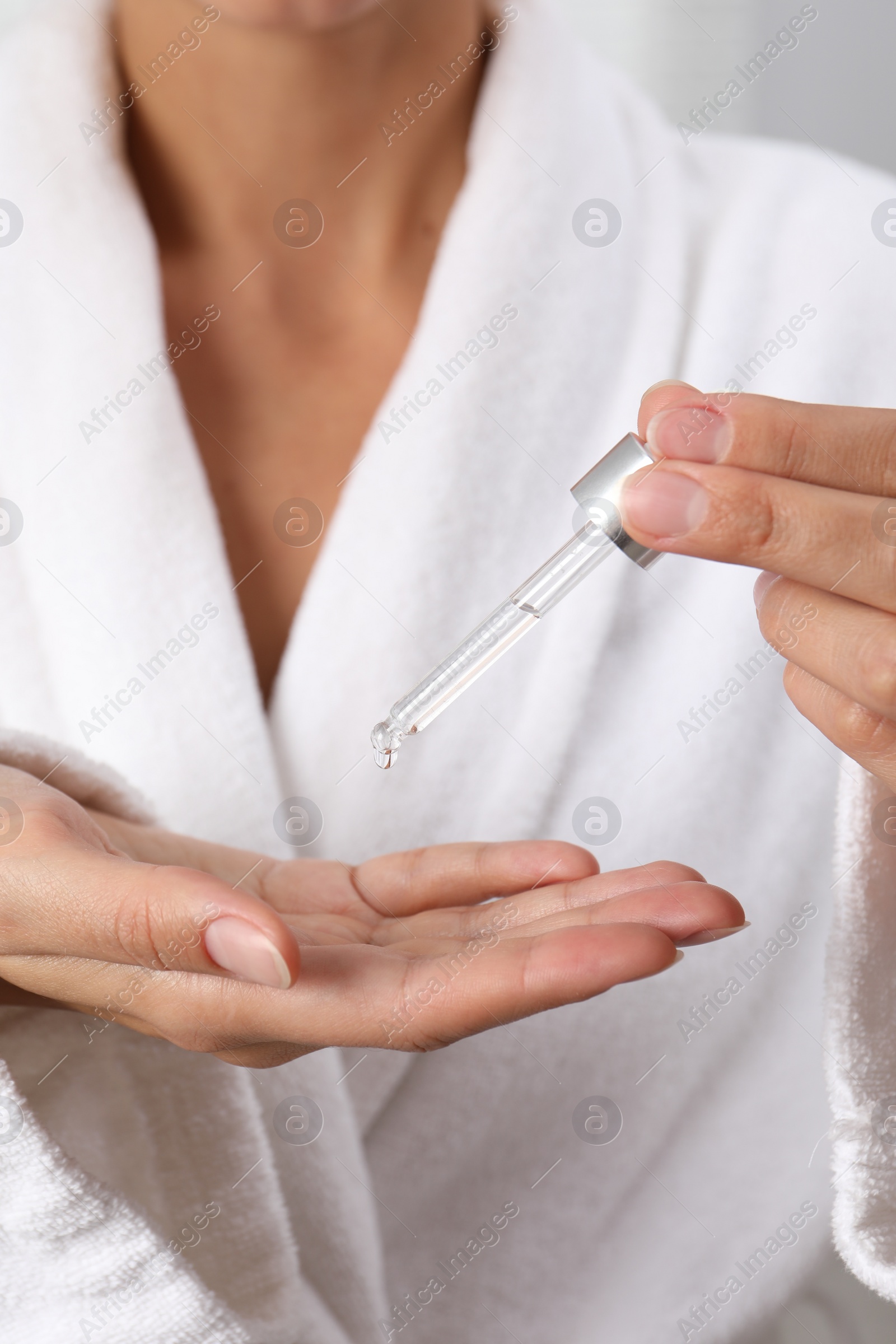 Photo of Woman applying cosmetic serum onto her hand, closeup