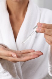 Photo of Woman applying cosmetic serum onto her hand, closeup