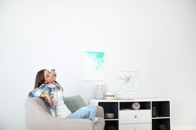 Photo of Young woman relaxing under air conditioner at home