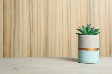 Artificial plant in flower pot on light grey stone table. Space for text