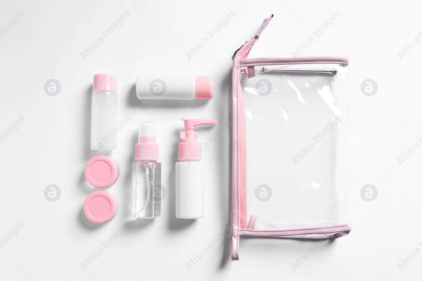 Photo of Cosmetic travel kit and plastic bag on white background, flat lay