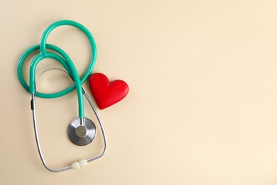 Photo of Stethoscope and red heart on beige background, top view. Space for text