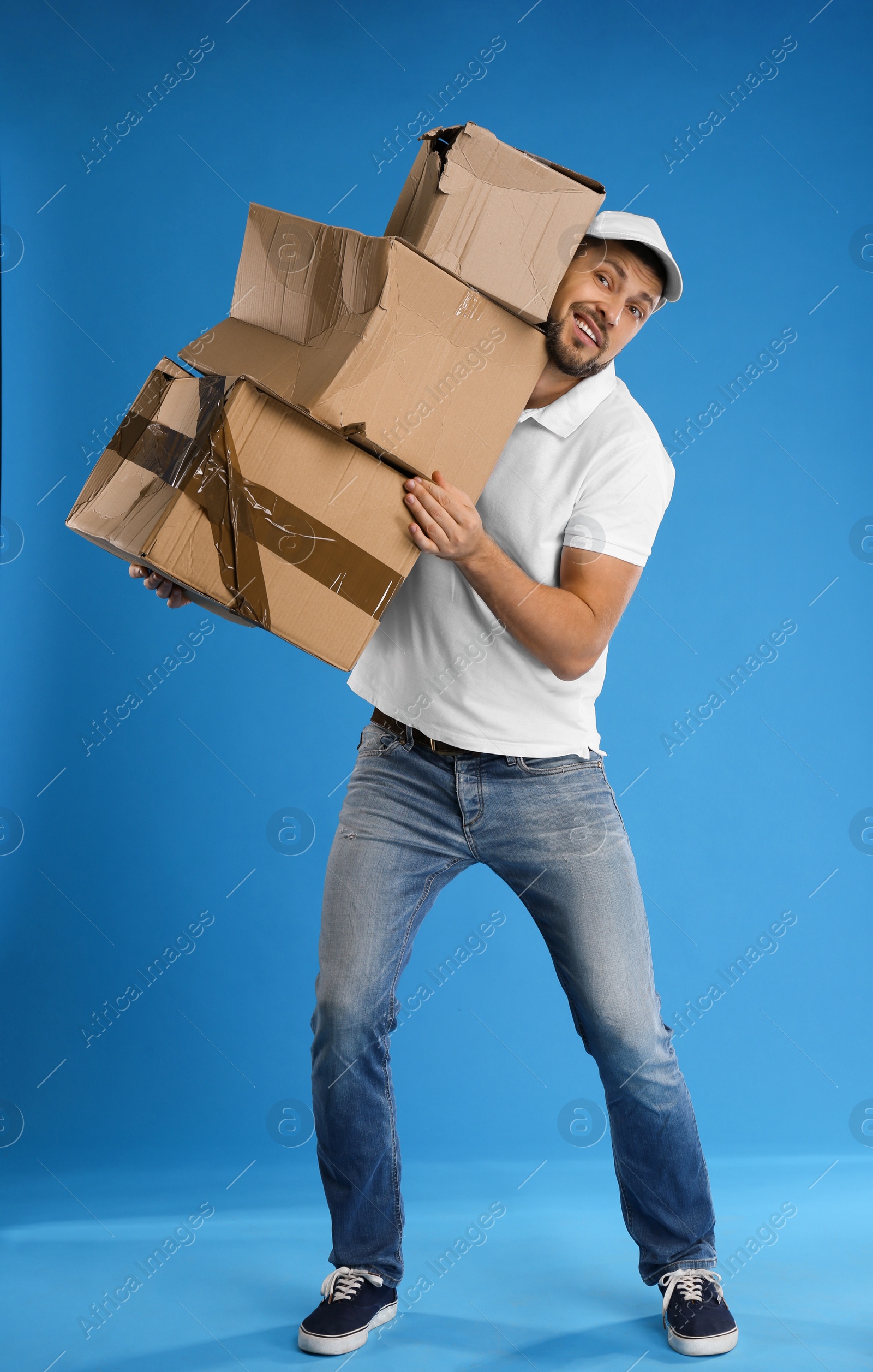 Photo of Emotional courier with damaged cardboard boxes on blue background. Poor quality delivery service