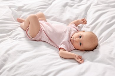 Photo of Cute little baby lying on white sheets