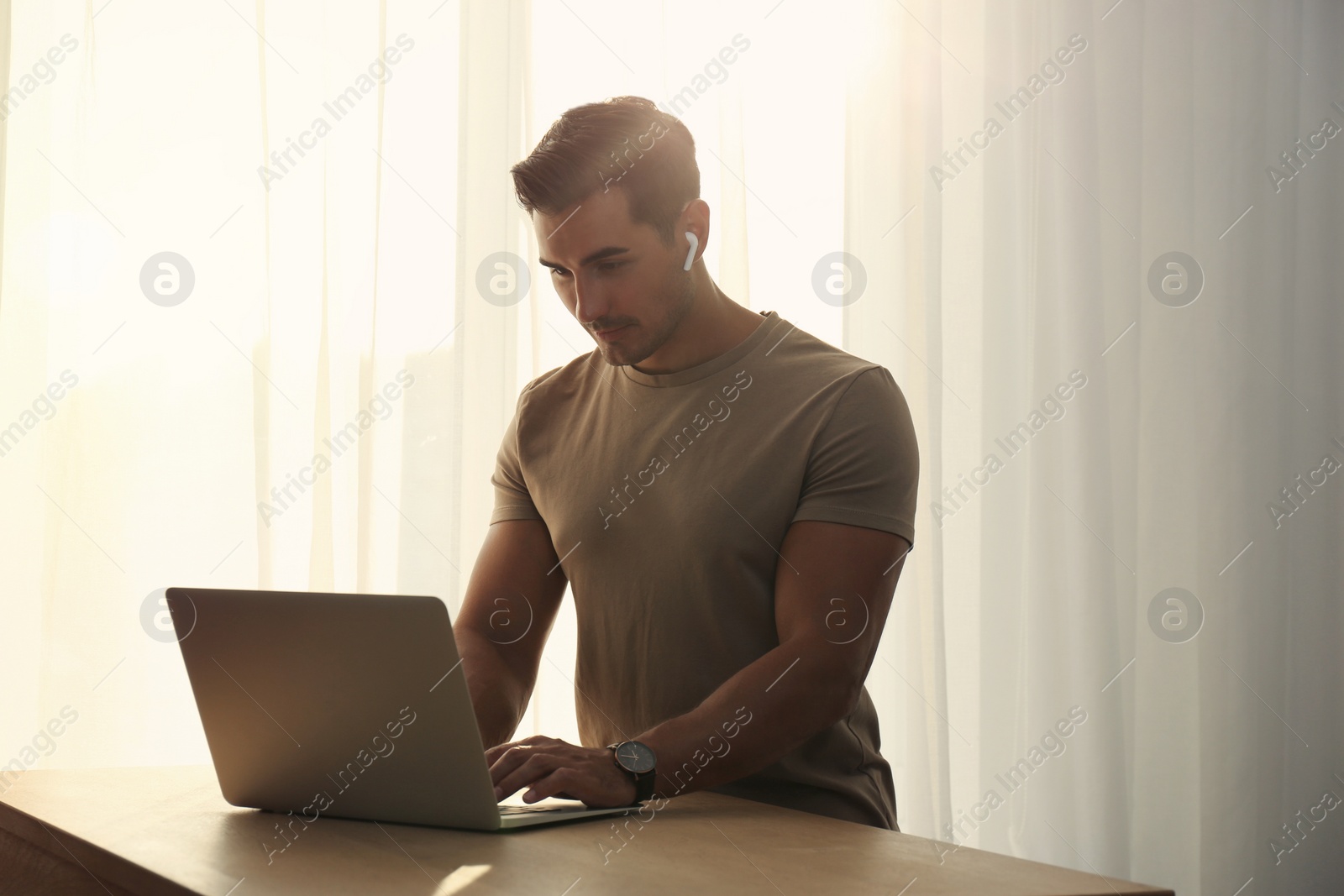 Photo of Portrait of young man with laptop at table indoors