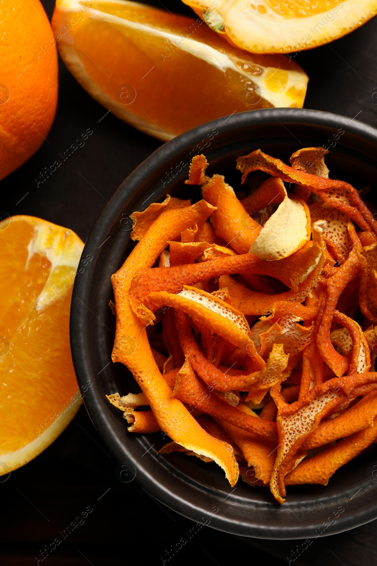 Photo of Bowl with dry orange peels and fresh fruits on table, flat lay