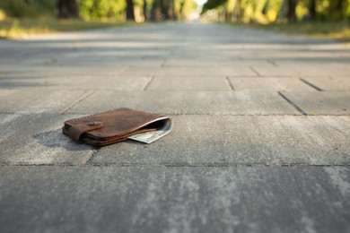 Photo of Brown leather purse on pavement outdoors, space for text. Lost and found