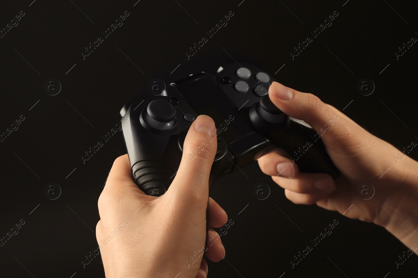 Photo of Woman holding video game controller on black background, closeup