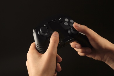 Woman holding video game controller on black background, closeup