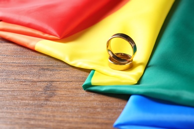 Photo of Wedding rings and rainbow flag on wooden table. Gay marriage