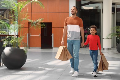Photo of Family shopping. Happy father and son with purchases in mall