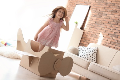 Adorable little child playing with cardboard plane at home