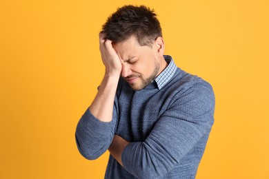 Photo of Man suffering from terrible migraine on yellow background