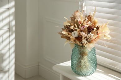 Photo of Beautiful dried flower bouquet in glass vase on white windowsill. Space for text