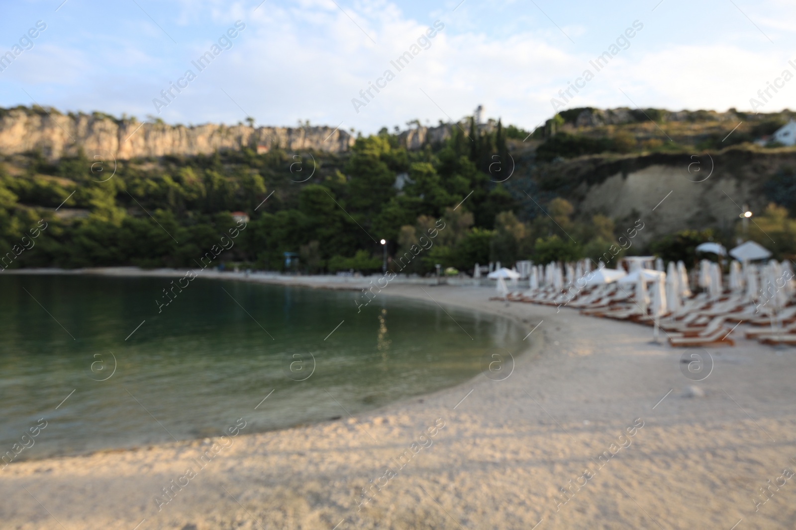 Photo of Blurred view of seashore with beach umbrellas and sunbeds on sunny day