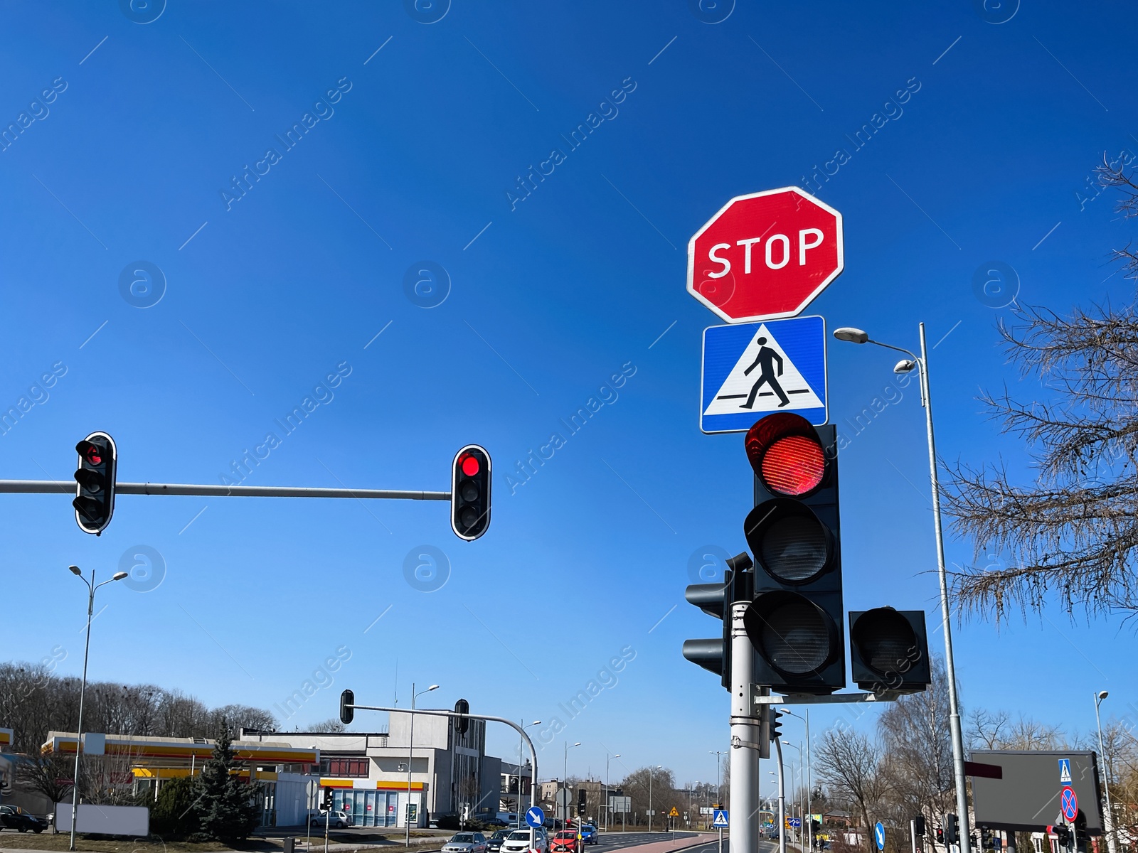 Photo of Traffic lights and road signs on pole against blue sky