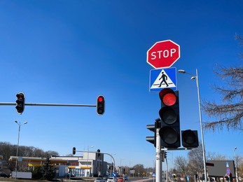 Photo of Traffic lights and road signs on pole against blue sky