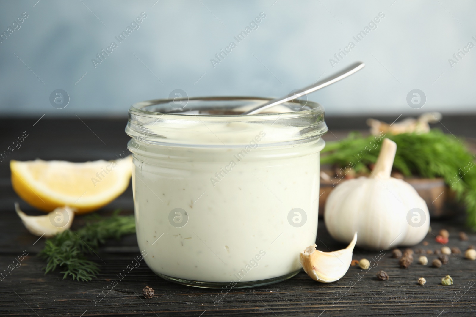 Photo of Composition with jar of garlic sauce on wooden table