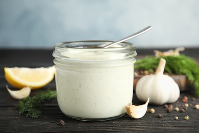 Photo of Composition with jar of garlic sauce on wooden table