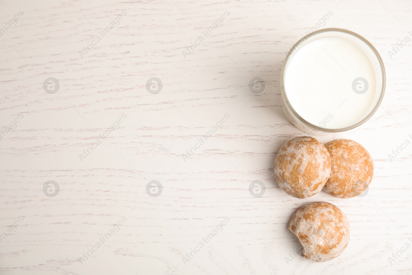 Photo of Tasty homemade gingerbread cookies and glass of milk on white wooden table, flat lay. Space for text