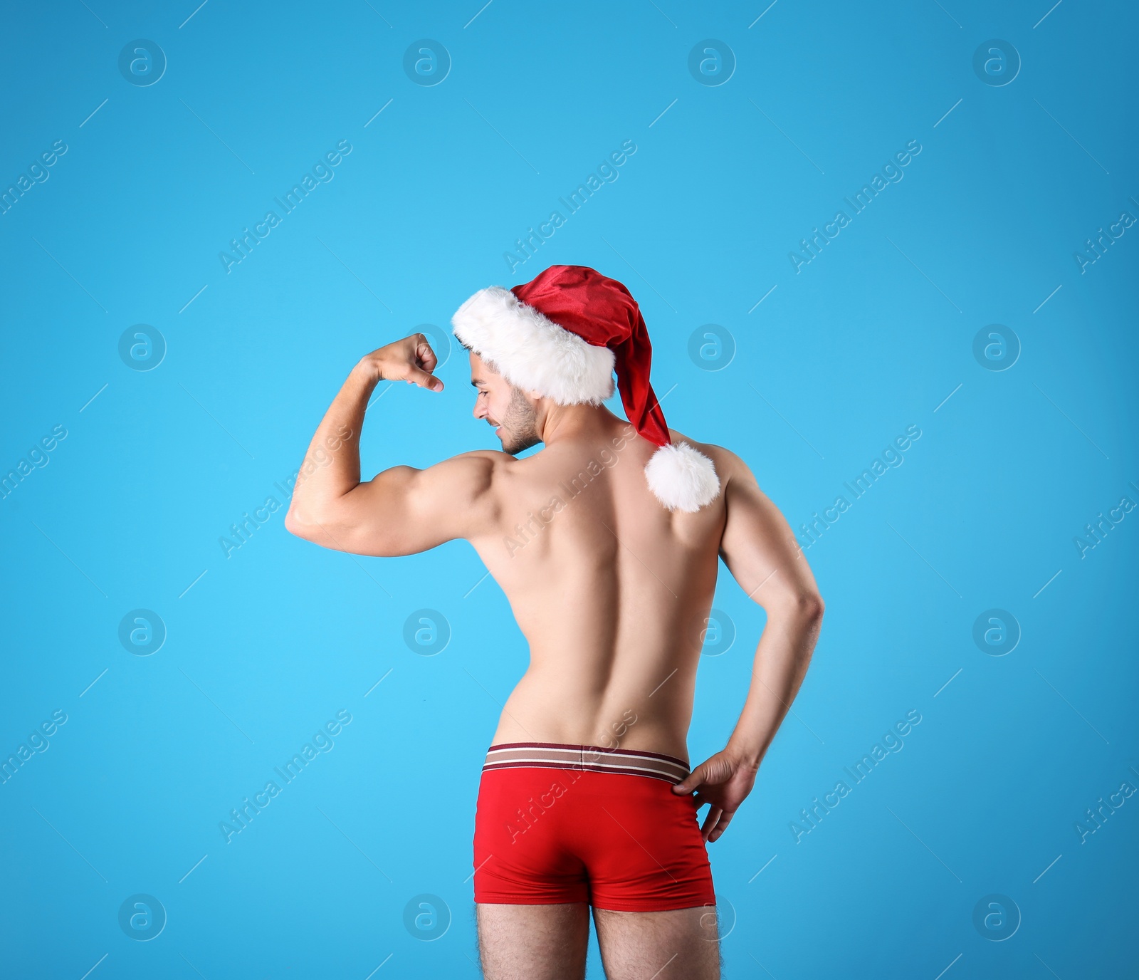 Photo of Shirtless young Santa Claus with sexy body on color background