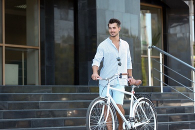 Photo of Handsome young hipster man with bicycle outdoors