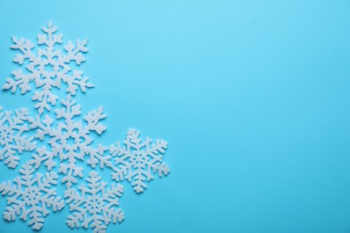 Photo of Beautiful decorative snowflakes on light blue background, flat lay. Space for text