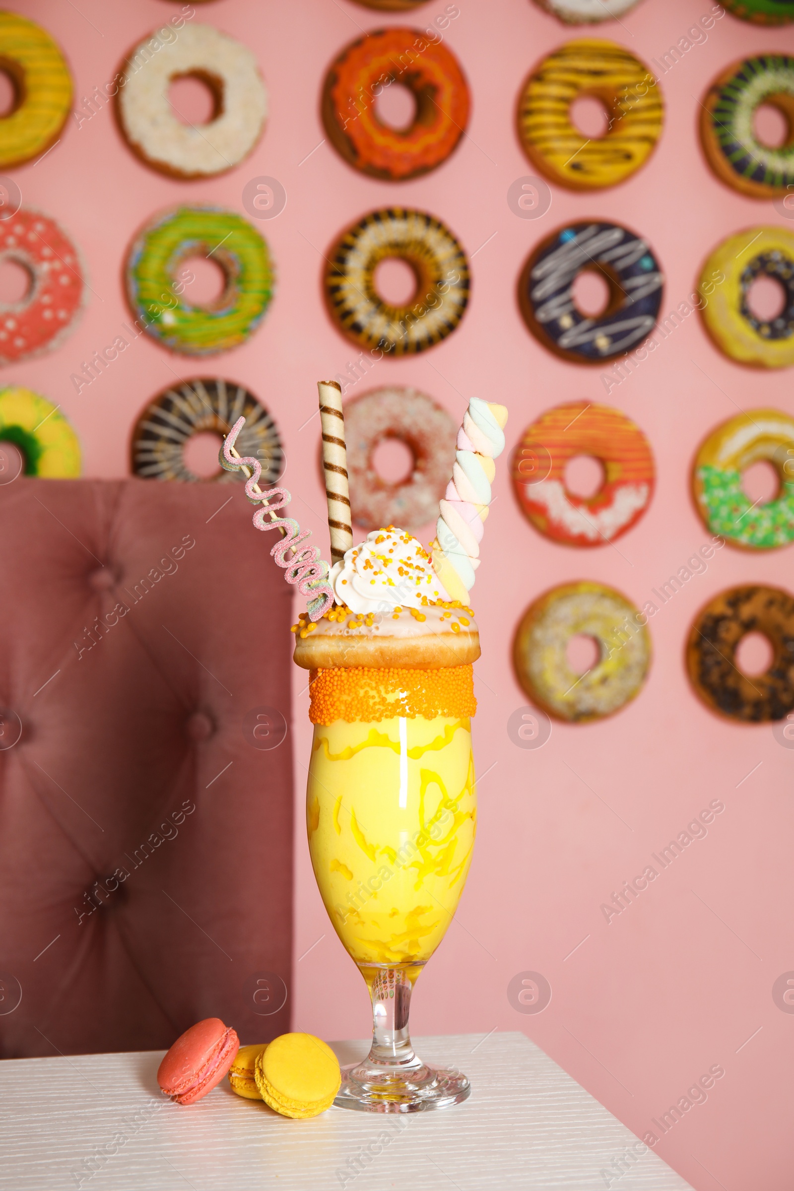 Photo of Glass of tasty milk shake with sweets on table indoors