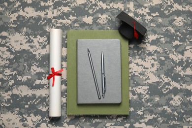 Photo of Stationery, diploma and mortarboard on camouflage background, flat lay. Military education