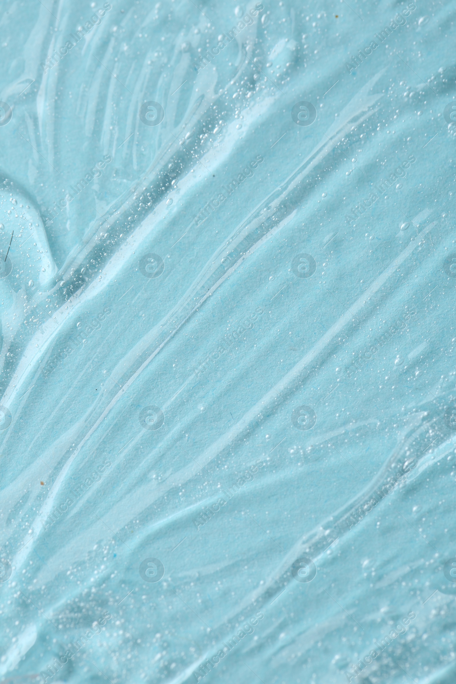 Photo of Clear cosmetic serum on light blue background, macro view