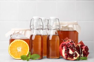 Tasty kombucha, fresh fruits and mint on white table