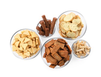 Different crispy rusks in bowls on white background, top view