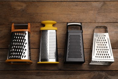Photo of Different modern graters on wooden table, flat lay