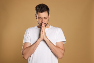 Man with clasped hands praying on beige background