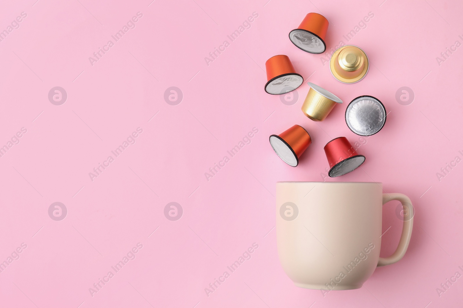 Photo of Many coffee capsules and cup on pink background, top view. Space for text