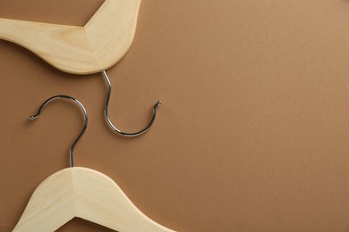 Photo of Wooden hangers on brown background, top view. Space for text