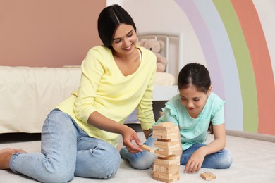 Happy mother and daughter playing Jenga together in bedroom. Single parenting