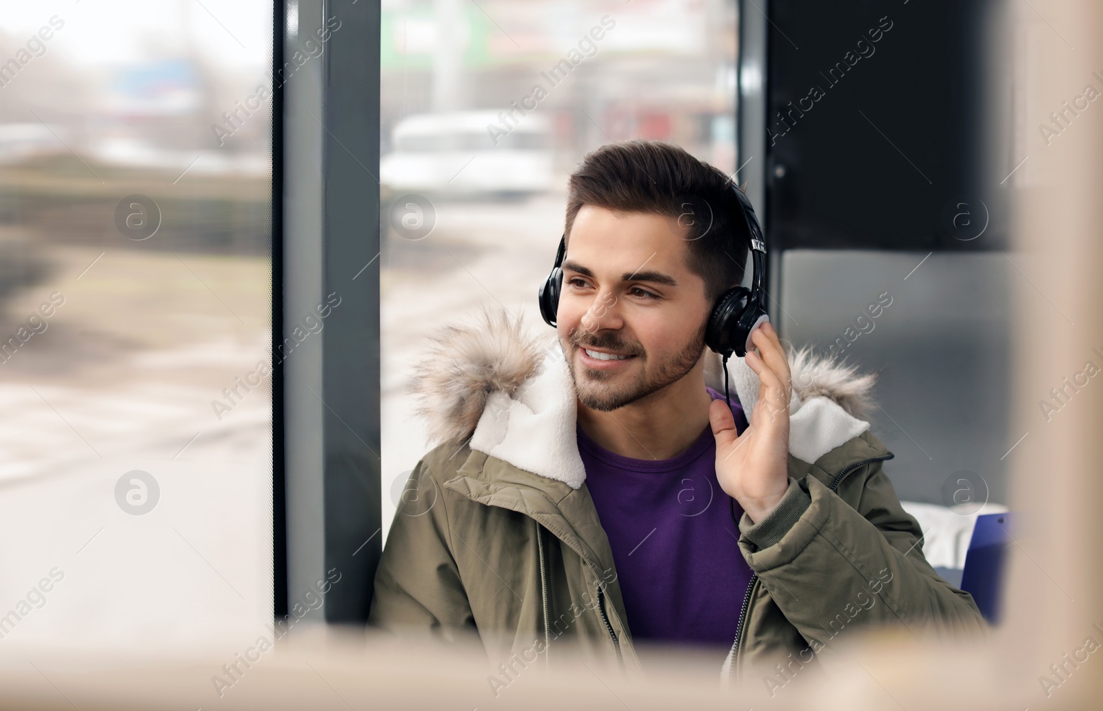 Photo of Young man listening to music with headphones in public transport