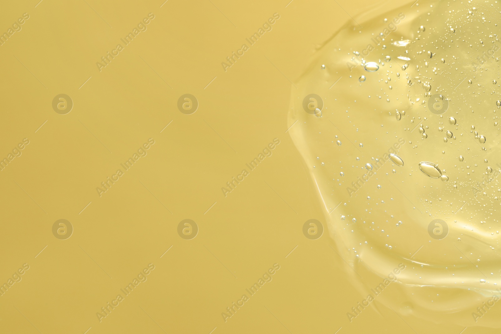 Photo of Transparent cleansing gel on pale yellow background, top view with space for text. Cosmetic product