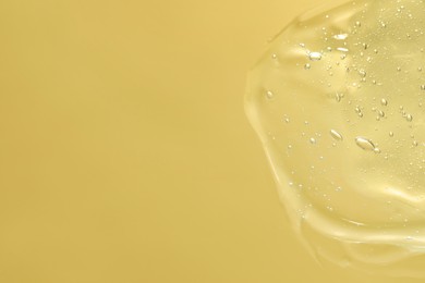 Transparent cleansing gel on pale yellow background, top view with space for text. Cosmetic product