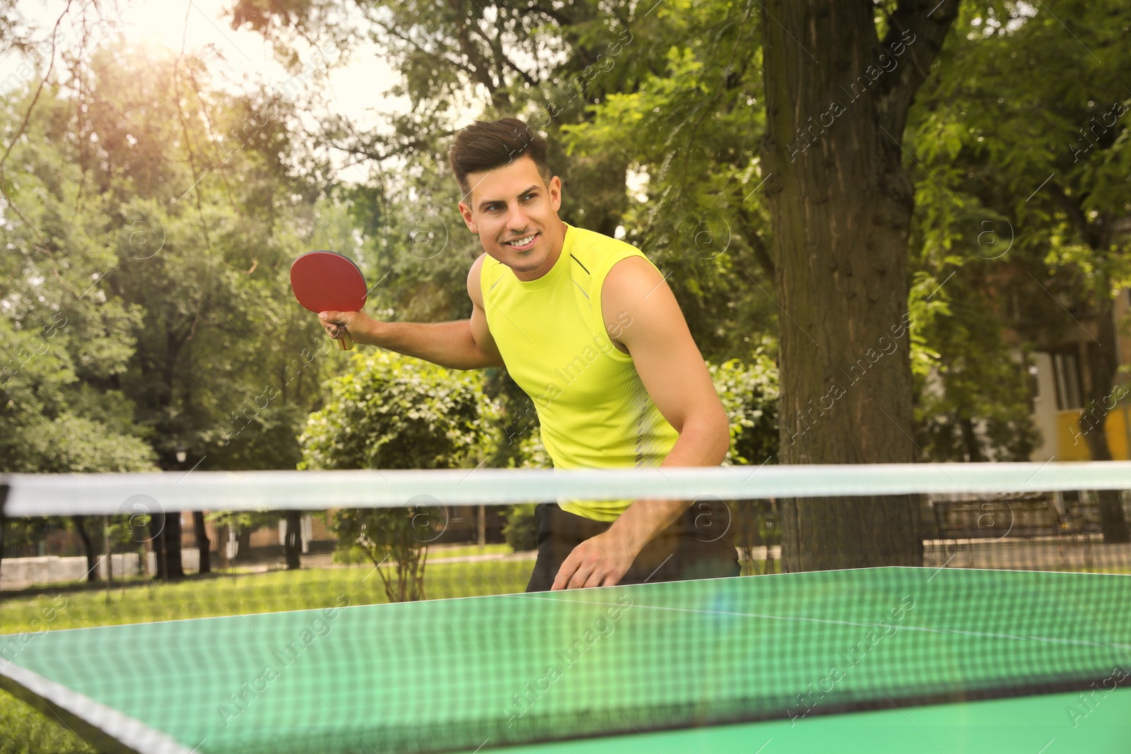 Photo of Man playing ping pong in park on summer day