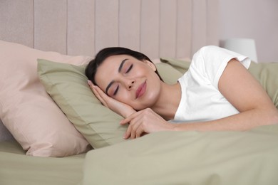 Photo of Woman sleeping in comfortable bed with green linens