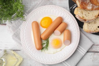 Photo of Delicious boiled sausages and fried eggs served on wooden table, flat lay
