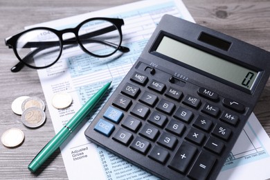 Photo of Tax accounting. Calculator, document, pen and coins on wooden table, closeup