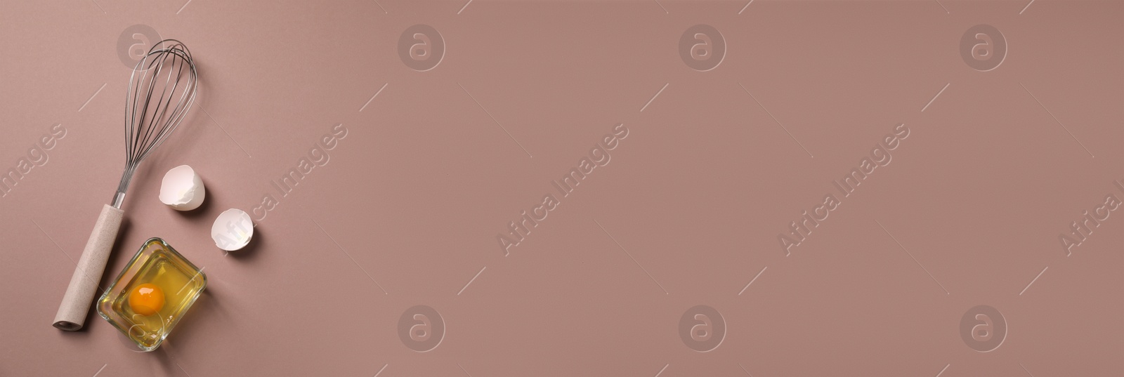 Image of Metal whisk, raw egg and shells on brown background, flat lay. Banner design with space for text