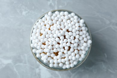 Photo of Many cotton buds in glass jar on light grey marble table, top view