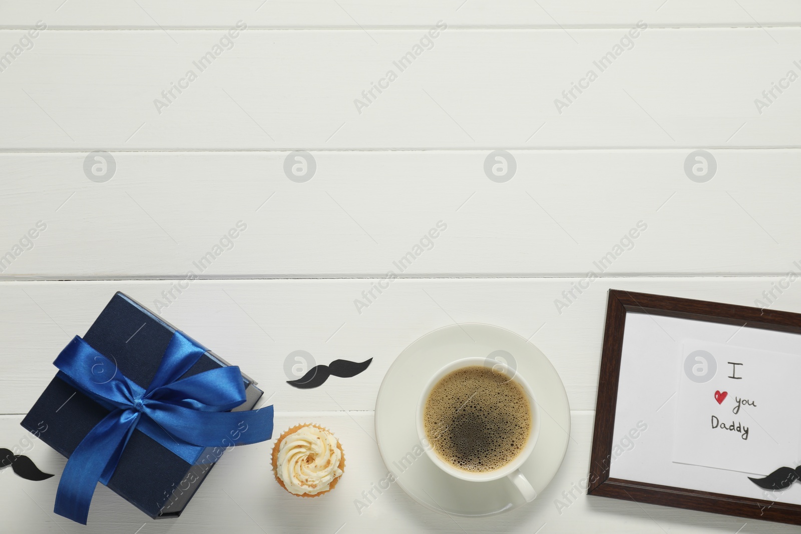 Photo of Father's day celebration. Flat lay composition of card with phrase I Love You Daddy and cup of aromatic coffee on white wooden table. Space for text